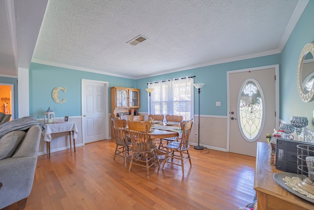 dining room featuring a textured ceiling, hardwood / wood-style flooring, and ornamental molding