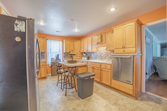 kitchen with sink, a center island, light brown cabinetry, a breakfast bar, and appliances with stainless steel finishes