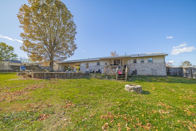 back of house with a yard, a deck, and an outdoor fire pit