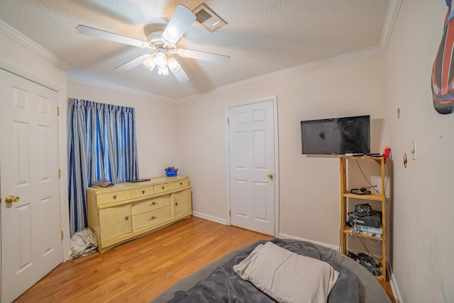 bedroom with a textured ceiling, ceiling fan, wood-type flooring, and ornamental molding