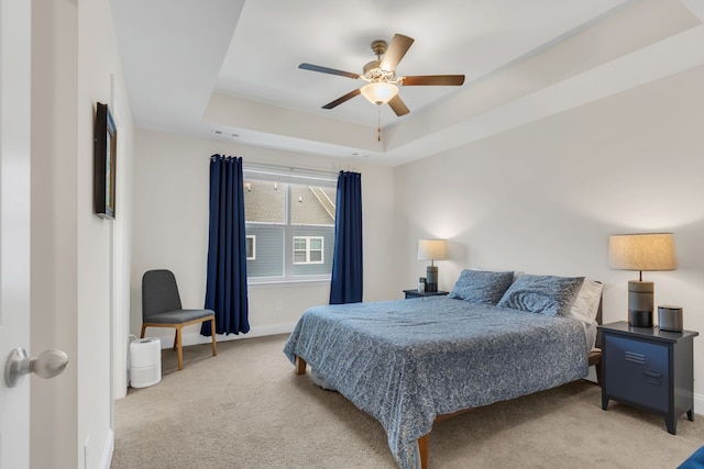 bedroom featuring a tray ceiling, ceiling fan, and light carpet