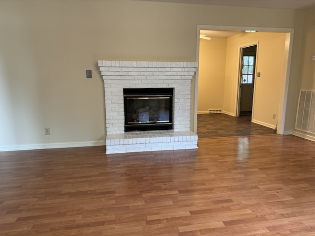 unfurnished living room with hardwood / wood-style floors and a brick fireplace