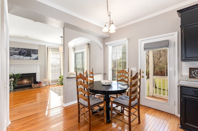 dining space with light hardwood / wood-style floors, ornamental molding, and a notable chandelier