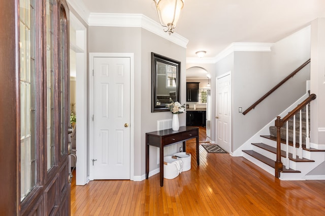 entryway with hardwood / wood-style floors and crown molding