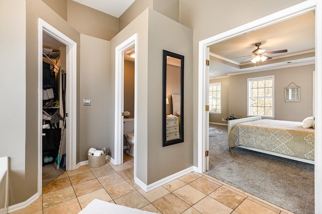 bedroom featuring light carpet, ornamental molding, a raised ceiling, ceiling fan, and connected bathroom