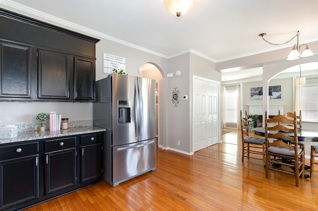 kitchen featuring light stone countertops, crown molding, a notable chandelier, stainless steel fridge with ice dispenser, and light hardwood / wood-style floors