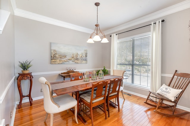 dining space featuring an inviting chandelier, light hardwood / wood-style flooring, and crown molding