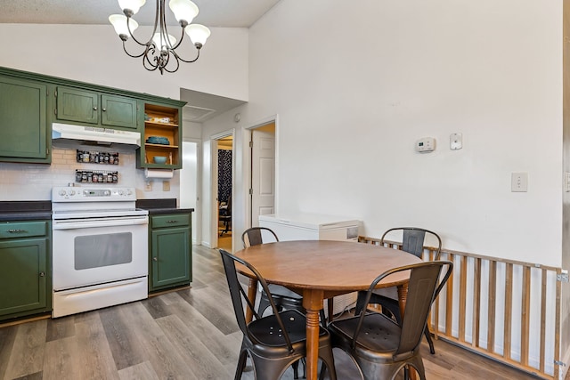 kitchen featuring electric range, green cabinets, light wood-type flooring, and an inviting chandelier