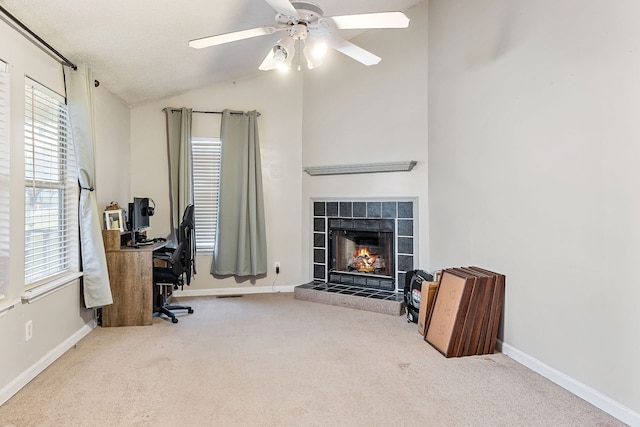 office area with light colored carpet, vaulted ceiling, ceiling fan, and a tiled fireplace