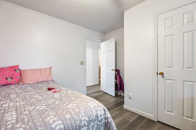 bedroom with a textured ceiling and dark wood-type flooring