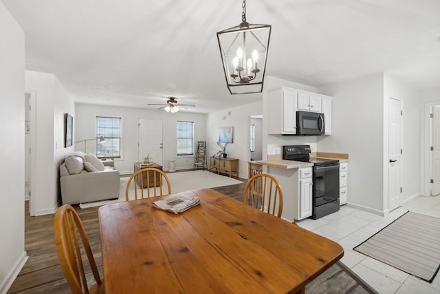 tiled dining space with ceiling fan with notable chandelier