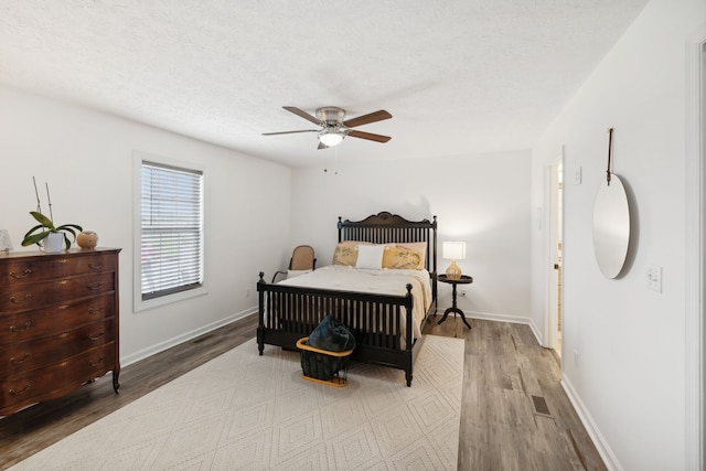 bedroom with hardwood / wood-style floors, ceiling fan, and a textured ceiling