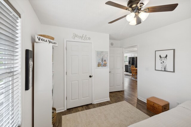 bedroom with ceiling fan, dark hardwood / wood-style floors, stainless steel refrigerator with ice dispenser, and a closet