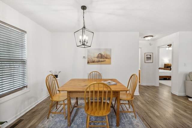 dining room featuring ceiling fan with notable chandelier and dark hardwood / wood-style flooring