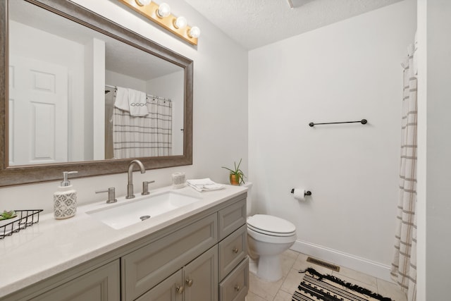 bathroom with tile patterned floors, vanity, a textured ceiling, and toilet