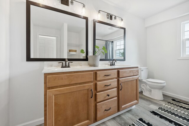 bathroom with hardwood / wood-style floors, vanity, a healthy amount of sunlight, and toilet