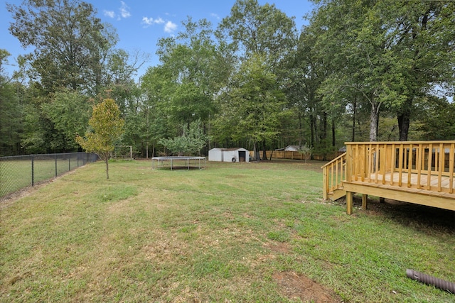 view of yard featuring a storage unit, a trampoline, and a wooden deck