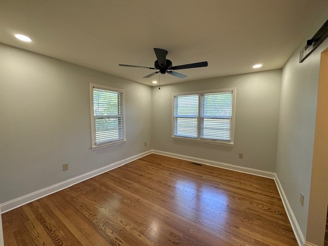 spare room featuring a barn door, a wealth of natural light, ceiling fan, and wood-type flooring