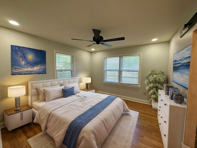 bedroom with wood-type flooring, a barn door, and ceiling fan