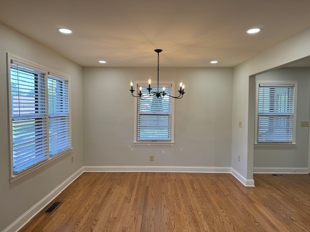 unfurnished dining area featuring hardwood / wood-style floors and a notable chandelier