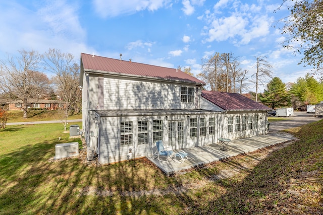 back of house with a patio and a lawn