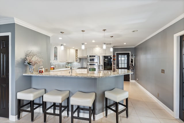 kitchen featuring stainless steel appliances, kitchen peninsula, decorative light fixtures, white cabinets, and ornamental molding