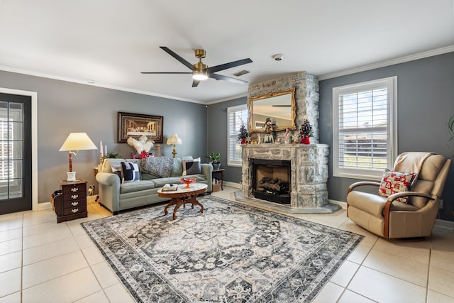 living room featuring a stone fireplace, crown molding, light tile patterned flooring, and ceiling fan