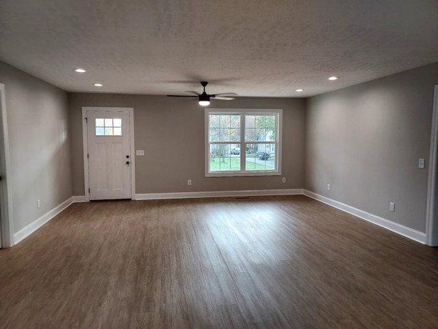 unfurnished living room featuring a textured ceiling, ceiling fan, and dark wood-type flooring