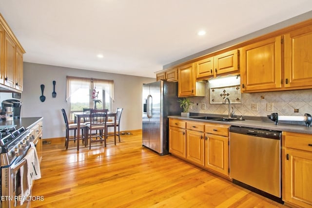 kitchen featuring appliances with stainless steel finishes, light wood-type flooring, backsplash, and sink