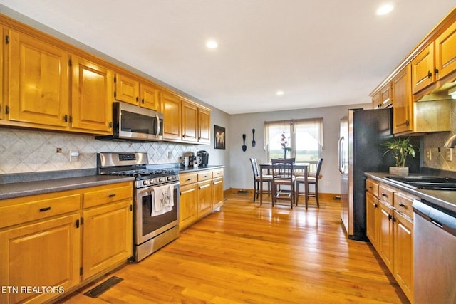 kitchen with light wood-type flooring, sink, appliances with stainless steel finishes, and tasteful backsplash