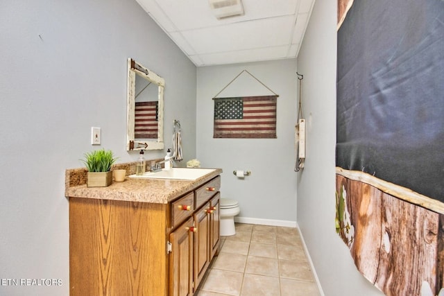 bathroom featuring toilet, vanity, a paneled ceiling, and tile patterned floors