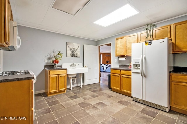 kitchen featuring a paneled ceiling, white appliances, and dark tile patterned flooring