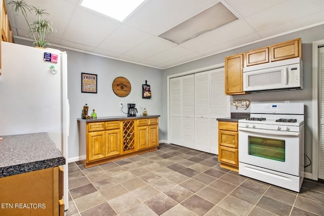 kitchen with a paneled ceiling, dark tile patterned floors, and white appliances