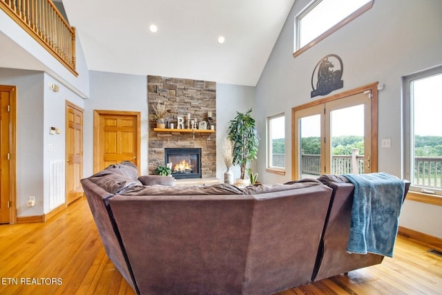 living room with a fireplace, high vaulted ceiling, and light hardwood / wood-style floors