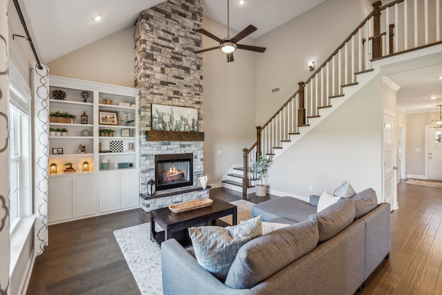 living room featuring dark hardwood / wood-style floors, high vaulted ceiling, ceiling fan, and a stone fireplace