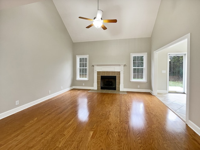 unfurnished living room with hardwood / wood-style flooring, ceiling fan, a fireplace, and high vaulted ceiling