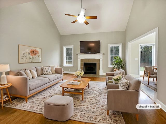 living room featuring a tile fireplace, ceiling fan, high vaulted ceiling, and wood-type flooring