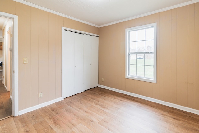 unfurnished bedroom with light hardwood / wood-style flooring, a closet, and ornamental molding