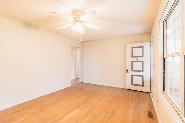 empty room featuring ceiling fan, light wood-type flooring, and crown molding