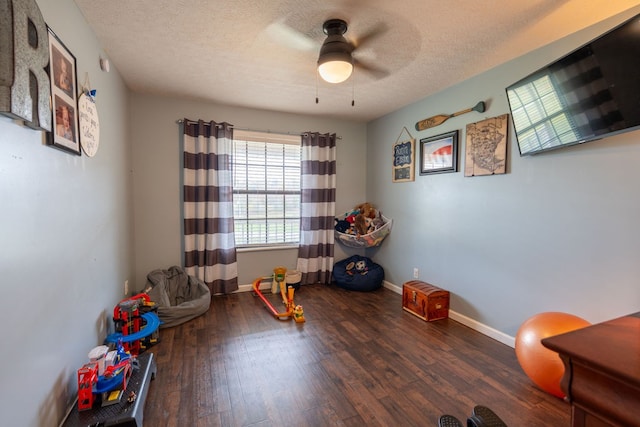 rec room with a textured ceiling, ceiling fan, and dark hardwood / wood-style floors