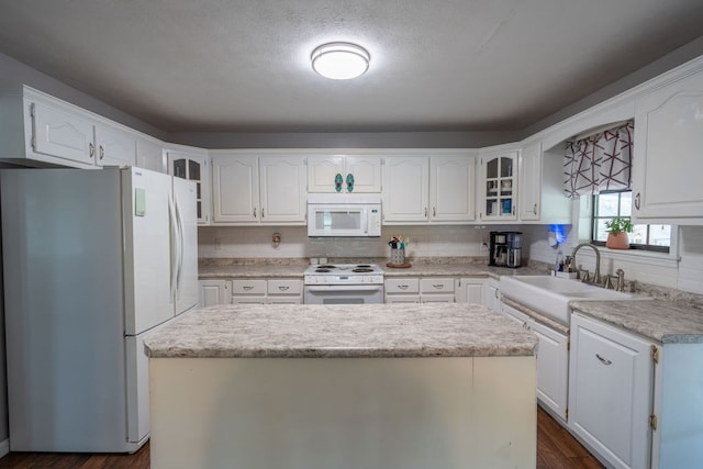 kitchen featuring white cabinetry, sink, a kitchen island, and white appliances