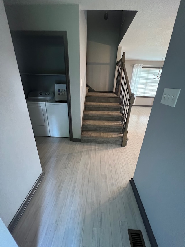 stairway with washing machine and dryer and hardwood / wood-style flooring