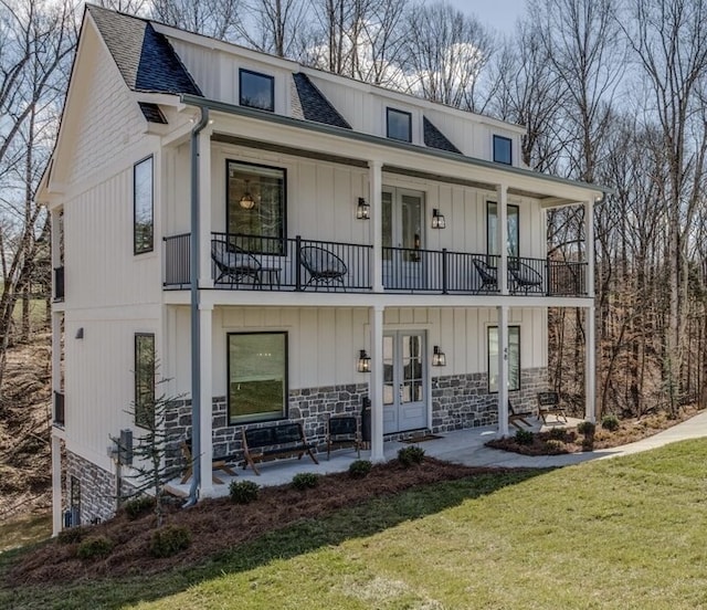 view of front of house featuring a balcony, french doors, a porch, and a front lawn