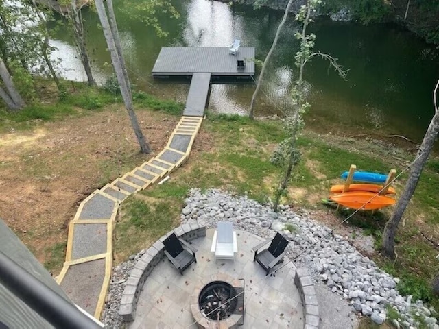 view of yard featuring a patio, an outdoor fire pit, a dock, and a water view