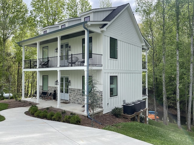 rear view of house with central air condition unit, french doors, and a balcony