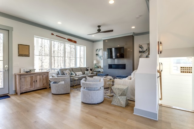 living room with ornamental molding, ceiling fan, and light hardwood / wood-style flooring