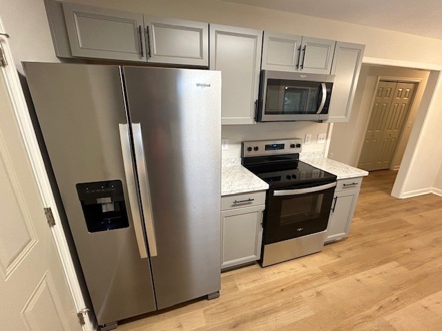 kitchen with gray cabinets, light wood-type flooring, and stainless steel appliances