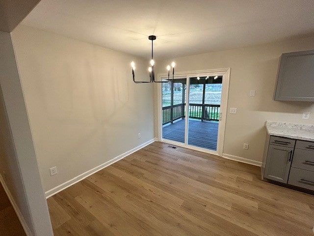 unfurnished dining area with a chandelier and light wood-type flooring