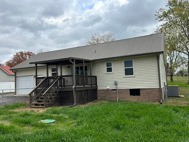 rear view of house featuring a lawn, central AC unit, and a garage