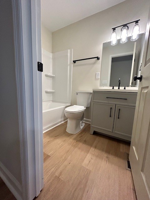 full bathroom with vanity, hardwood / wood-style flooring, toilet, and shower / bathtub combination